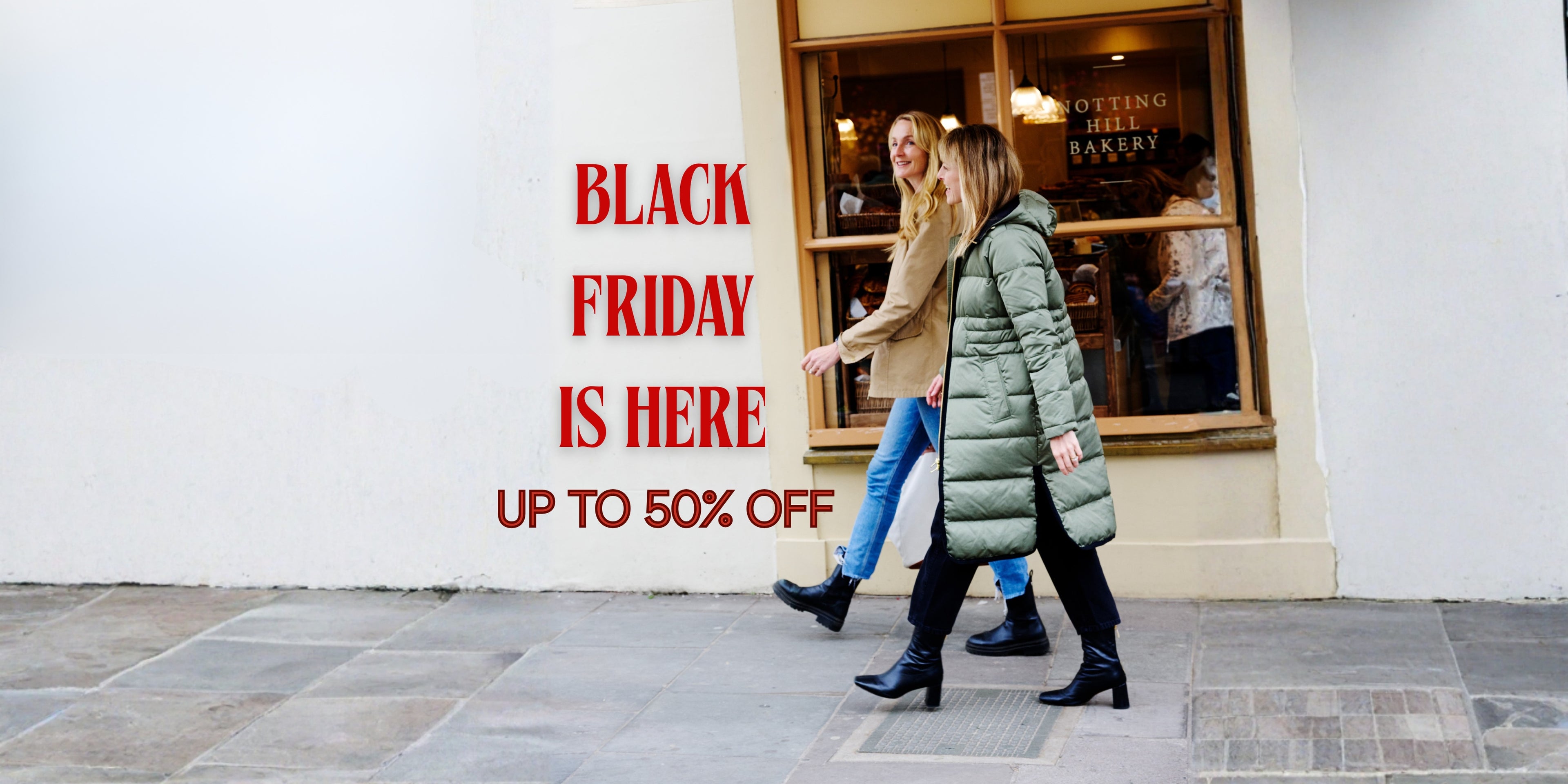 Two people walking past a store with a Black Friday sale sign.